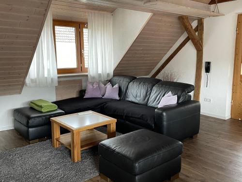 a living room with a black leather couch and a table at Sonniges Ferienapartment am Alten Binauer Schloss in Binau