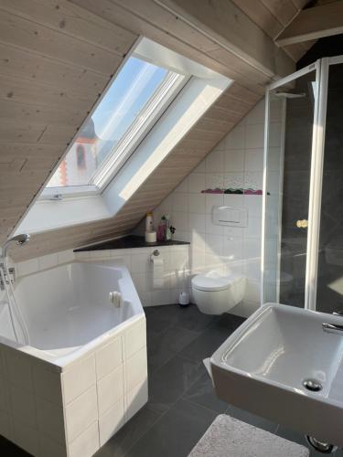 a bathroom with a tub and a toilet and a skylight at Sonniges Ferienapartment am Alten Binauer Schloss 