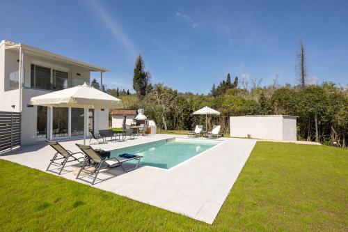 una piscina con sillas y una sombrilla en un patio en VILLA ELENA PRIVATE POOL Kontokali villas en Kontokali