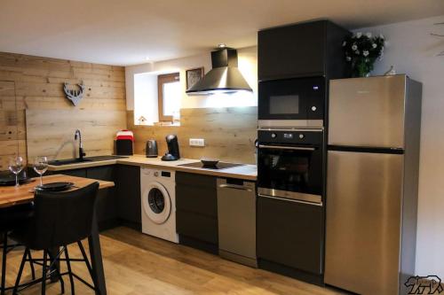 a kitchen with a stainless steel refrigerator and a table at Gîte de la Ravanne in Ramonchamp