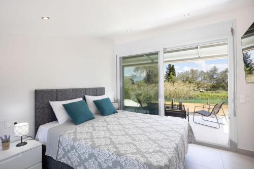 a white bedroom with a bed and a large window at VILLA ELENA PRIVATE POOL Kontokali villas in Kontokali