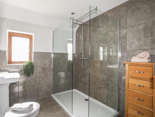 a bathroom with a glass shower and a toilet at Long House in Beaumaris
