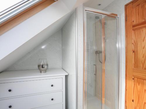a white bathroom with a shower and a white dresser at Long Cottage in Beaumaris