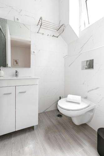 a white bathroom with a toilet and a sink at Refúgio da Nazaré in Nazaré