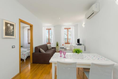 a white living room with a table and a couch at Apartment San Giovanni - Sea View in Rovinj