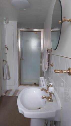 Baño blanco con lavabo y espejo en AROHA, en Glastonbury