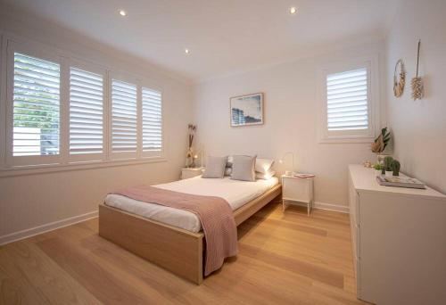 1 dormitorio con 1 cama en una habitación con ventanas en SALTY SNOOZE - Your Coastal Holiday House, en Avalon