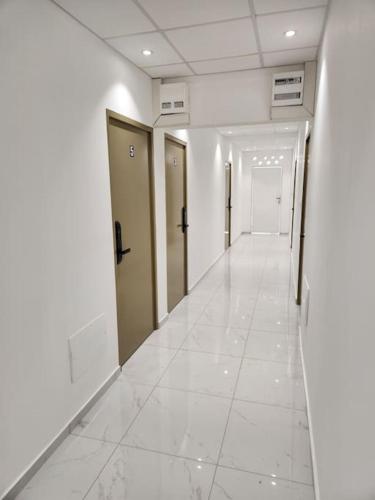a hallway of an office building with white floors and doors at Hello-Guyane, Marina 3, Studio Prestige 5 étoiles in Saint-Laurent du Maroni