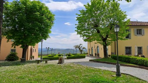 Dépendance in Villa Albachiara e Primaluce في كارمينيانو: حديقة فيها جلسة واشجار ومبنى