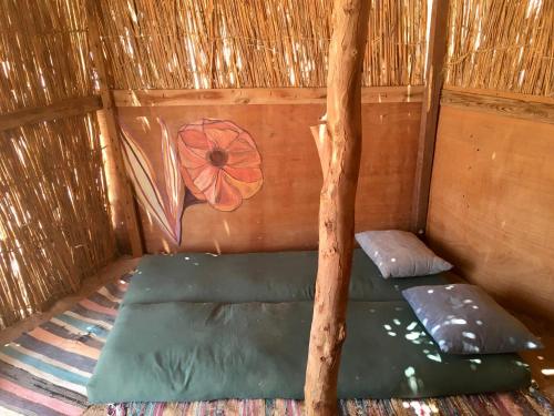 a room with a green bed in a straw hut at Peace land camp in Nuweiba