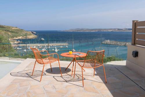 a table and chairs on a patio with a view of the ocean at Gozo Harbour Views, Mgarr Heights in Mġarr