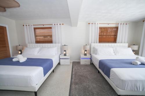 two beds in a bedroom with white walls and windows at Florida Mango Island /pool/beach/Legacy Trail in Venice