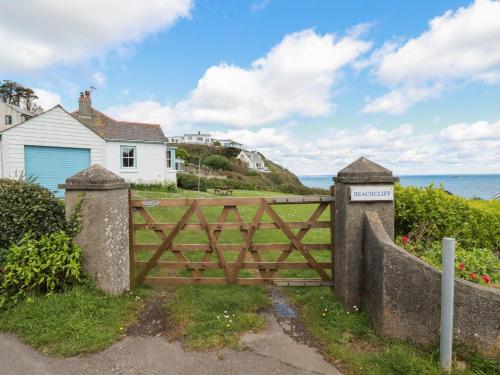 a wooden gate in front of a house and the ocean at Beachcliff in Gorran Haven