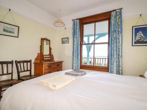 a bedroom with a bed with a window and a mirror at Beachcliff in Gorran Haven