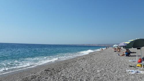 a beach with people and umbrellas and the ocean at Le Decime in Mascali