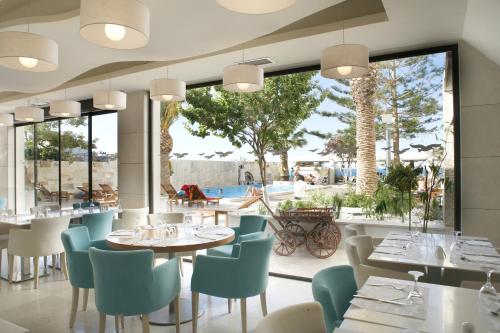 Glaros Beach Hotel في خيرسونيسوس: مطعم بطاولات وكراسي ونافذة كبيرة