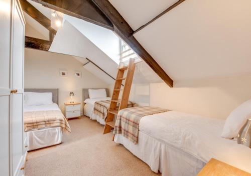 a attic bedroom with two beds and a ladder at Waldo Hafod y Mor in Tenby