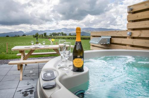 a bottle of champagne in a bath tub with a table at Waenfechan Glamping with Hot Tubs in Colwyn Bay