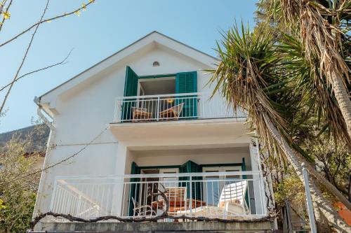 a white house with chairs on a balcony at Detached Villa with stunning views in Njivice, Montenegro in Njivice