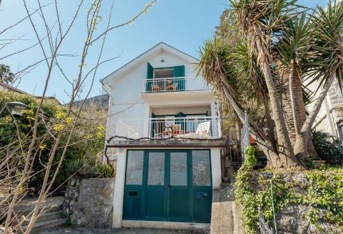 une maison avec une porte verte et des palmiers dans l'établissement Detached Villa with stunning views in Njivice, Montenegro, à Njivice