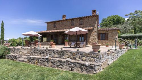 ein Steinhaus mit Sonnenschirmen und einer Steinmauer in der Unterkunft Piccolo Relais Galletto di Marzo Spa e relax solo per due in Paciano