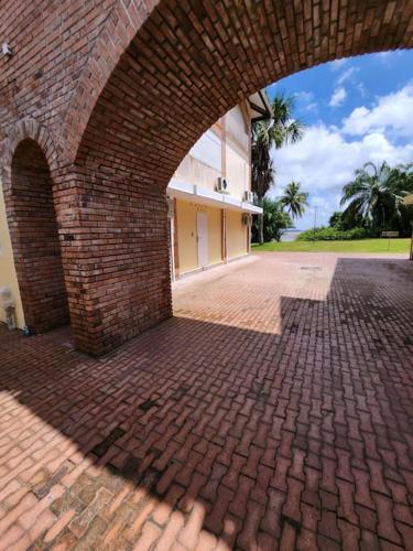 an archway of a brick building with a brick courtyard at Hello-Guyane, Marina 4, Studio Prestige 5 étoiles in Saint-Laurent du Maroni