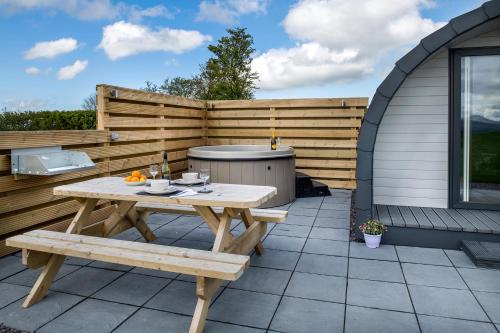 a wooden picnic table and bench on a patio at Waenfechan Glamping with Hot Tubs in Colwyn Bay