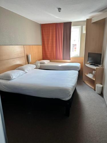 a hotel room with two beds and a television at ibis Carlisle City Centre in Carlisle