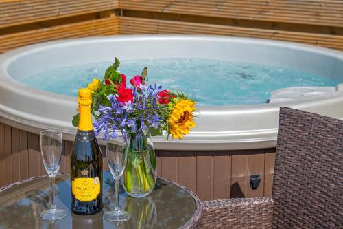 a table with a bottle of wine and flowers and a swimming pool at Waenfechan Glamping with Hot Tubs in Colwyn Bay
