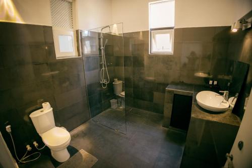 W łazience znajduje się toaleta, umywalka i prysznic. w obiekcie Lankahuts Villa w Negombo
