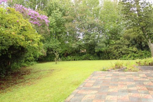a garden with a grass field and trees at Serenity Graskop, 3 bedroom A-Frame cottage in Graskop
