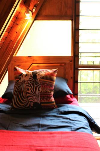 a bed with two zebra pillows on top of it at Serenity Graskop, 3 bedroom A-Frame cottage in Graskop