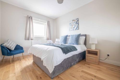 a bedroom with a large bed and a blue chair at Harbour View Apartment at Royale Court Apartments Portrush in Portrush