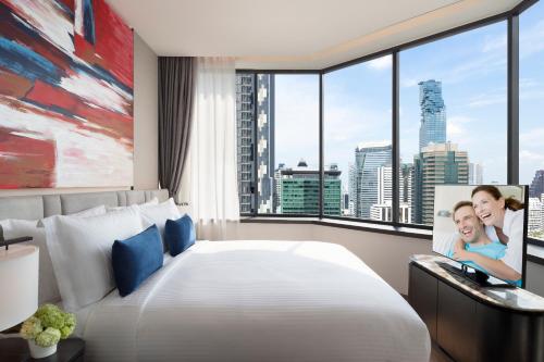 a bedroom with a large bed and a large window at Ascott Embassy Sathorn Bangkok in Bangkok