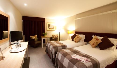 a hotel room with two beds and a flat screen tv at Westmorland Hotel Tebay in Tebay