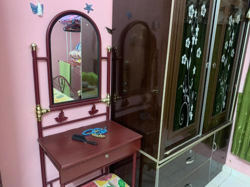 a bathroom with a wooden dresser and a mirror at D’baroh Homestay in Kampong Tanjong Karang