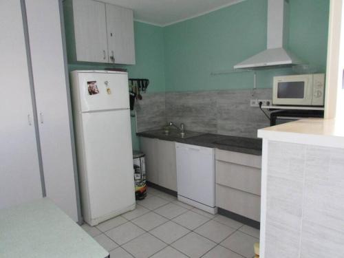 La cuisine est équipée d'un réfrigérateur blanc et d'un four micro-ondes. dans l'établissement Appartement proche du Lydia, au Barcarès