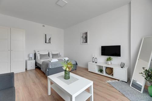 a white living room with a bed and a tv at Downtown Apartments Old Town Stolarska in Gdańsk