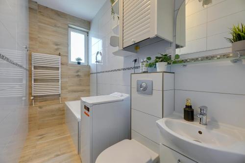 a white bathroom with a toilet and a sink at Downtown Apartments Old Town Stolarska in Gdańsk