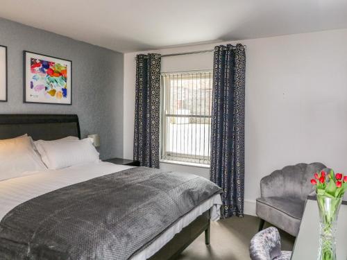 a bedroom with a bed and a chair and a window at 30 Dart Marina in Dartmouth