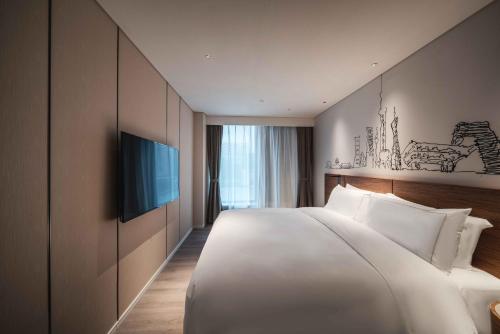 UrCove by Hyatt Shanghai Lujiazui Expo Center في شانغهاي: سرير أبيض كبير في غرفة الفندق