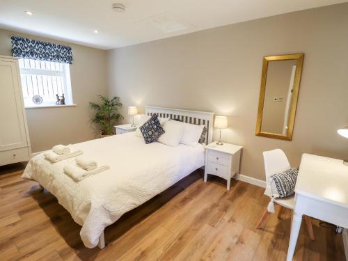 una camera con letto, scrivania e specchio di The Asparagus Shed a Sleaford