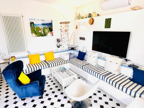 a living room with blue and white furniture and a flat screen tv at Casa Molo 13 in Mattinata