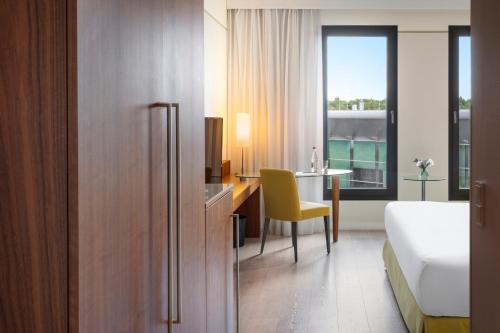 a hotel room with a bed and a desk and a table at Melia Luxembourg in Luxembourg
