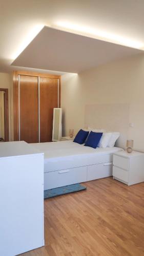 a large white bed with blue pillows in a room at Porta 116 - Free Private Parking in Vila Real