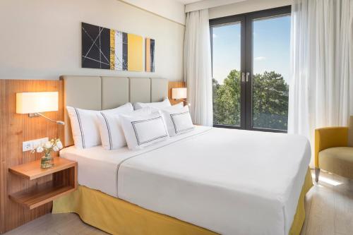 Un dormitorio con una gran cama blanca y una ventana en Melia Luxembourg, en Luxemburgo