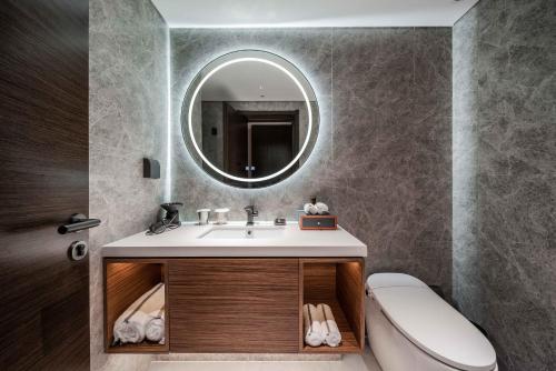 La salle de bains est pourvue d'un lavabo et d'un miroir. dans l'établissement UrCove by Hyatt Shanghai Lujiazui Expo Center, à Shanghai