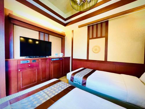 Schlafzimmer mit einem Bett und einem Flachbild-TV in der Unterkunft 嵐 Hotel Arashi 心斎橋店 in Osaka