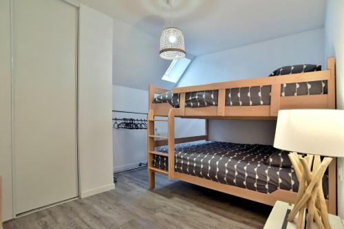 ein Schlafzimmer mit Etagenbetten und einem Stuhl in der Unterkunft Kermael - Appt vue mer et piscine partagée in Saint-Briac-sur-Mer
