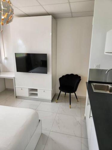 a white kitchen with a black chair and a television at Hello-Guyane, Marina 5, Studio Prestige 5 étoiles in Saint-Laurent du Maroni